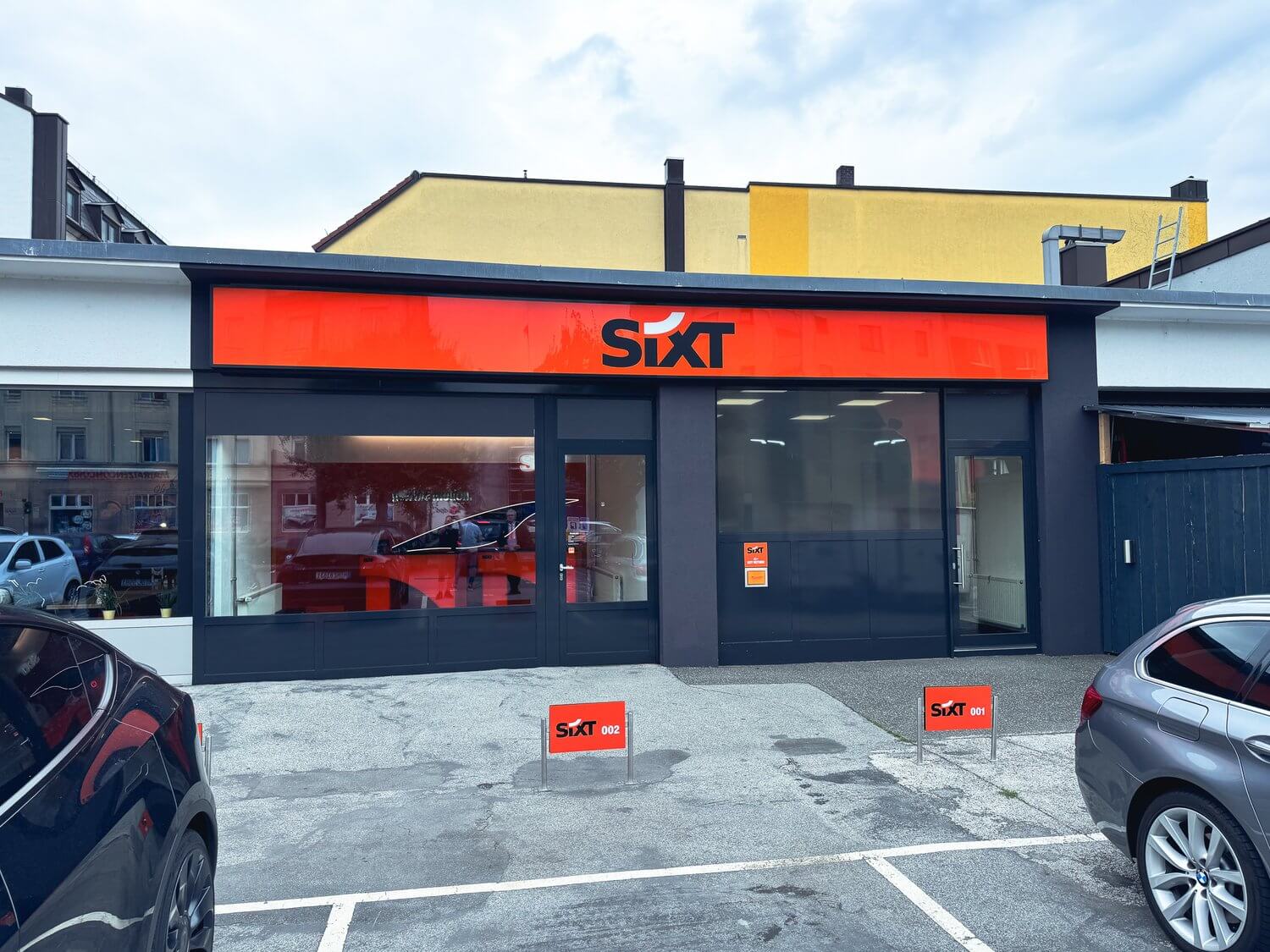 Frontansicht der SIXT-Filiale mit Fassadenblende und Parkplatzschildern